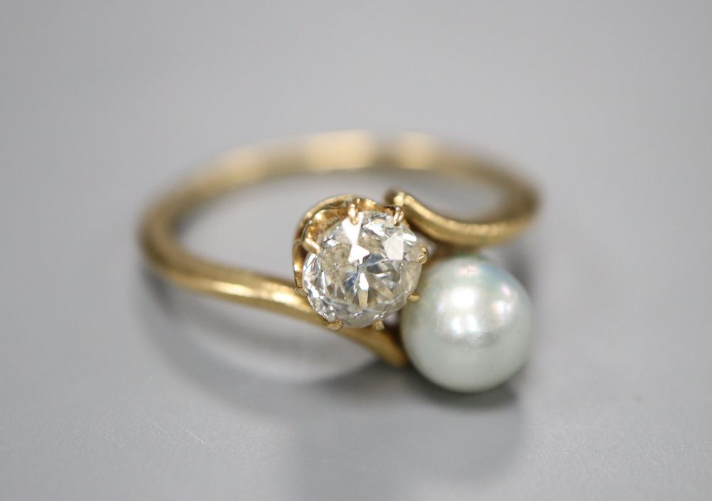 A yellow metal, diamond and cultured pearl set two stone crossover ring, size H/I, gross 2.4 grams.